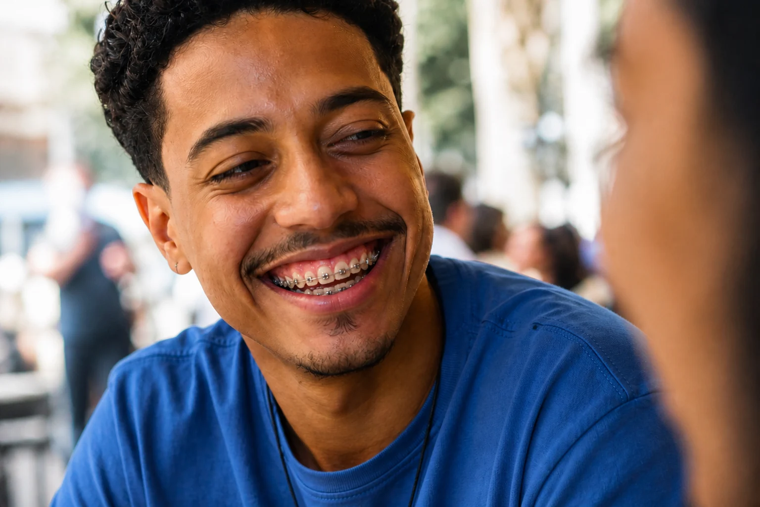 Jovem brasileiro sorrindo com aparelho ortodôntico metálico